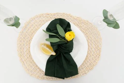 Table setting element lemon slice on a plate, green cloth napkin and yellow f Stock Photos