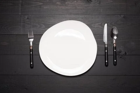 Table setting with empty white plate. Tableware on dark wooden background Stock Photos