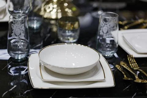 Table setting featuring a white porcelain bowl with a thin gold rim placed on Stock Photos