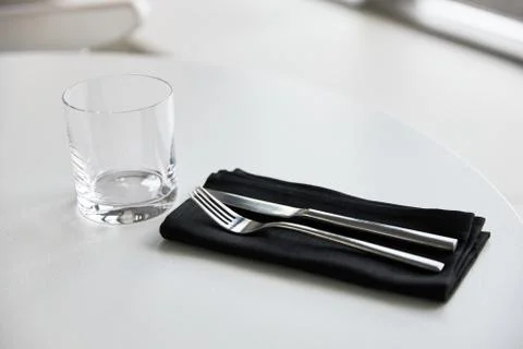 Table setting, glass cup, fork and a knife on a napkin, on a white background Stock Photos