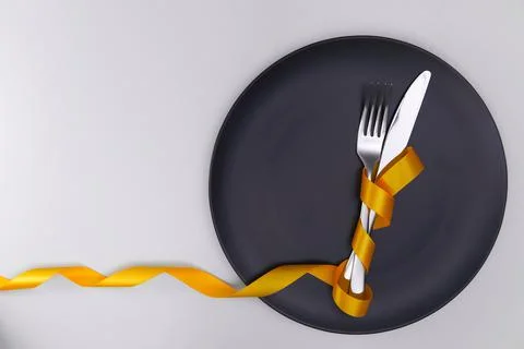 Table setting with gray plate and ribbon. Fork and knife for a holiday dinner on Stock Photos
