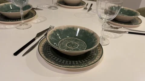 Table setting with green patterned dinnerware and glassware for home dining.. Stock Footage 331147339
