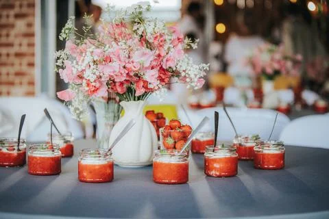Table setting with jars of strawberry dessert, fresh strawberries, and a fl.. Stock Photos