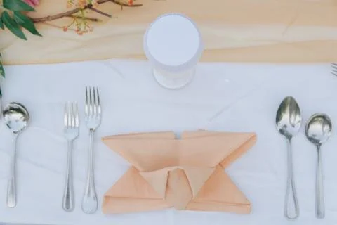 Table setting with a napkin folded into a triangle and silverware. Stock Photos