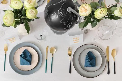 Table setting for Nobel prize day with globe and roses, top view Stock Photos