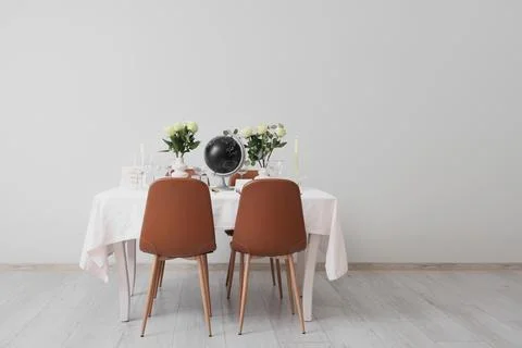 Table setting for Nobel prize day with globe and roses near light wall Stock Photos