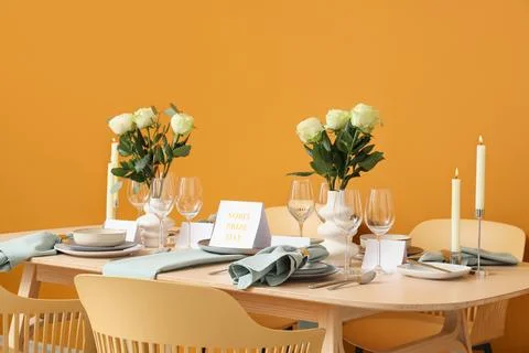 Table setting for Nobel prize day with burning candles and roses on orange ba Stock Photos