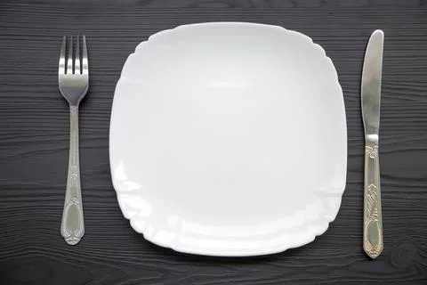 Table setting with one clean white plate, and a knife and fork laid out on a 库存照片