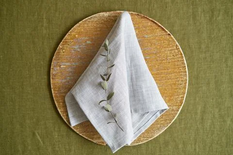 Table setting option. A linen grey napkin is neatly folded on a brown plate Stock Photos