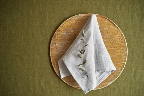 Table setting option. A linen grey napkin is neatly folded on a brown plate Stock Photos