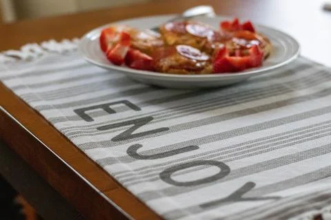 Table setting with a place mat and food saying enjoy Stock Photos