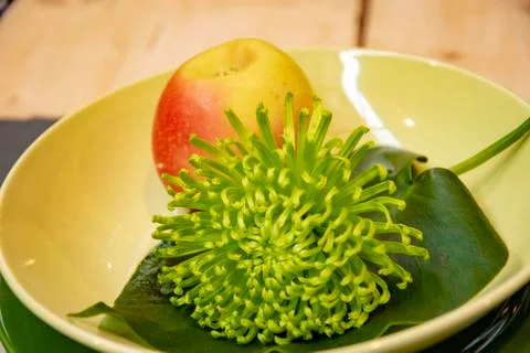 Table setting with plate of apple and a beautiful green flower Stock Photos