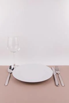 Table setting plate fork spoon and knife on gray background white plate Stock Photos