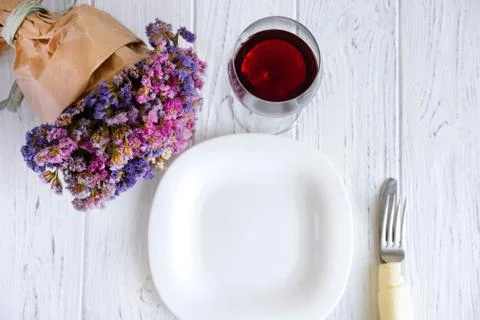Table setting. Plate on wooden background with gift box, cutlery, a glass of Stock Photos