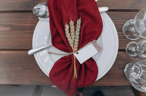 Table setting with plates, spikelets, towel and glasses on wooden table Foto stock