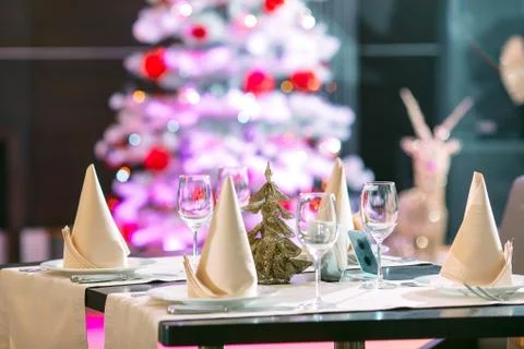 Table setting in the restaurant. Christmas tree on the background. Stock Photos
