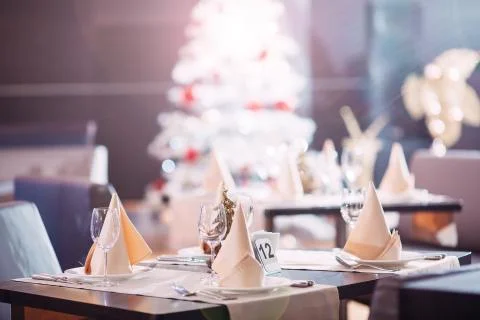 Table setting in the restaurant. Christmas tree on the background. Stock Photos