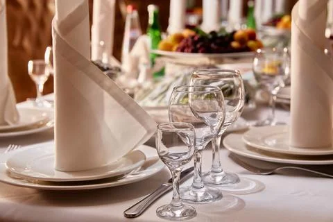 Table setting in the restaurant. Plates, glasses, forks and knives, napkins on Stock Photos