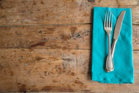 Table setting in retro style. Antique fork and knife on blue napkin and old w Stock Photos