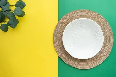 Table setting with table mat and dinnerware with green and yellow background. Stock Photos