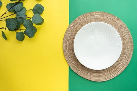 Table setting with table mat and dinnerware with green and yellow background. Stock Photos