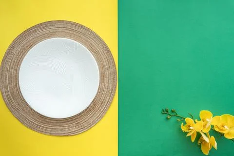 Table setting with table mat and dinnerware with green and yellow background. Stock-Fotos