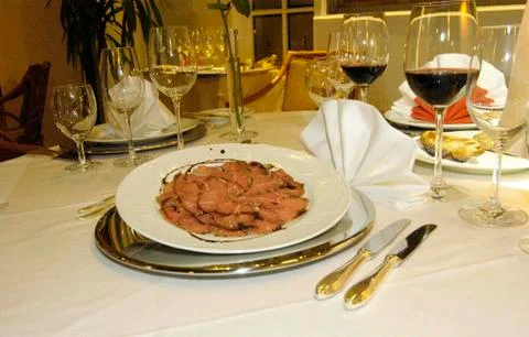Table setting with tablecloth, napkins, plates, knives, spoons, forks and gla Stock Photos