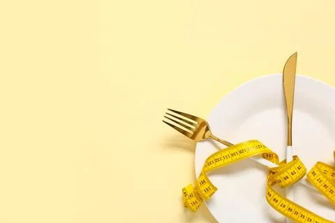 Table setting with tape measure on beige background. Intermittent fasting con Stock Photos