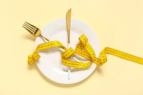 Table setting with tape measure on beige background. Intermittent fasting con Stock Photos