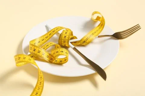 Table setting with tape measure on beige background. Intermittent fasting con Stock Photos