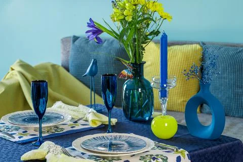 Table setting for two in blue and yellow colors against the background of a sofa Stock Photos
