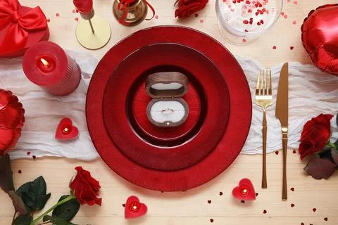 Table setting for Valentine's Day with engagement ring, candles and rose flow Stock Photos