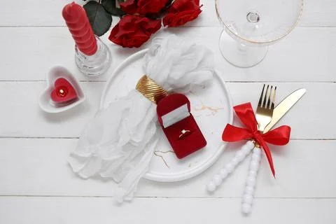 Table setting for Valentine's Day with engagement ring, candles and rose flow Stock Photos
