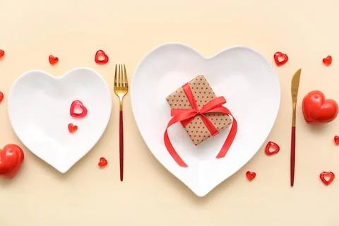 Table setting for Valentine's Day with gift box and decorative hearts on beig Stock Photos