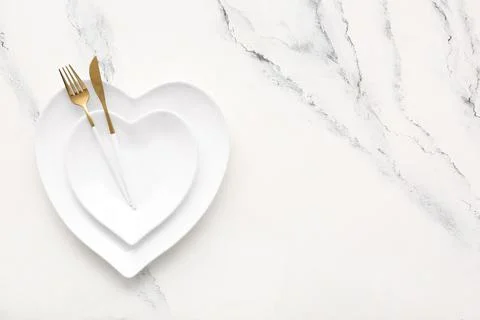 Table setting for Valentine's Day with heart-shaped plates on marble backgrou Stock Photos
