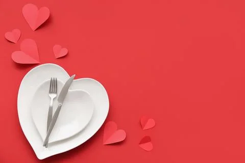 Table setting for Valentine's Day with paper hearts on red background Stock Photos
