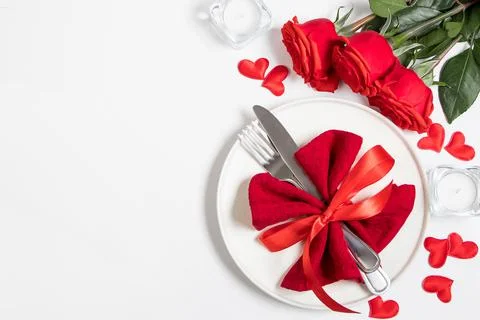 Table setting for valentine's day. Red roses and cutlery on a white backgroun Stock Photos
