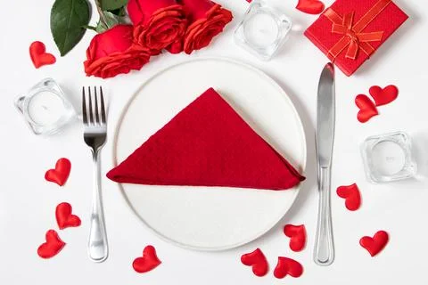 Table setting for valentine's day. Red roses and cutlery on a white backgroun Stock Photos