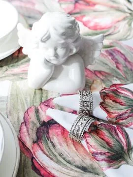 Table setting. White ceramic angel, napkins with red flowers Stock Photos