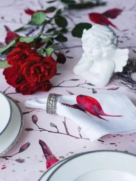 Table setting. White ceramic angel, napkins with red flowers Stock Photos