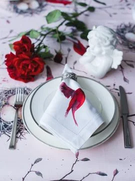Table setting. White ceramic angel, napkins with red flowers Stock Photos