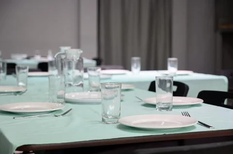 Table setting with white plates and glasses on a mint green tablecloth Stock Photos