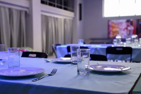 Table setting with white plates and glasses on a blue tablecloth Stock Photos