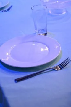 Table setting with white plates and glasses on a blue tablecloth Stock Photos