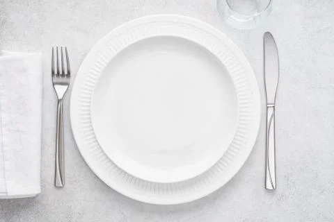 Table setting with white plates, glass, napkin, fork and knife. Stock Photos