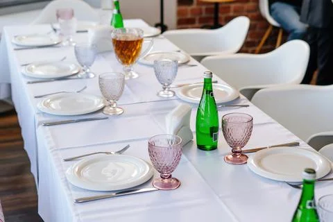 Table setting with white tablecloth, plates and cutlery laid out. Stock Photos