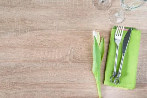 Table setting with white tulip, forged fork and knife on green napkin, set of Stock Photos