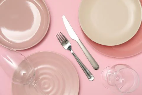 Table setting with wineglasses on pink background, top view Fotos de archivo
