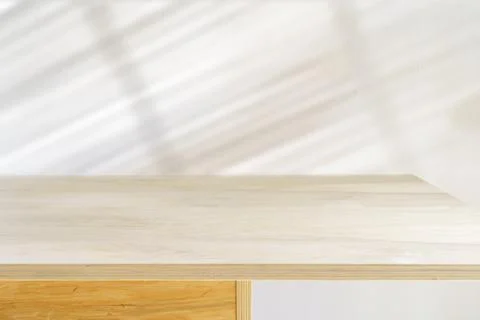 Table shadow background. Wooden table and white empty wall with plant shadows. Fotos Stock