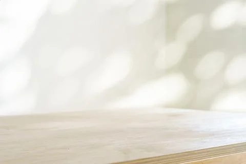 Table shadow background. Wooden table and white empty wall with plant shadows. Stock Photos